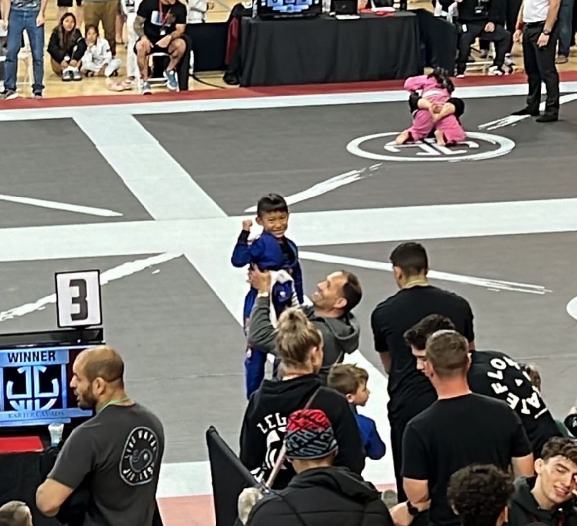 Professor Bob lifting young student after tournament win